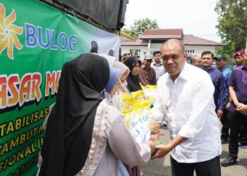 Pj Bupati Langkat H. M. Faisal Hasrimy, AP., M.Ap memegang satu karung beras. (Foto/Diskominfo).