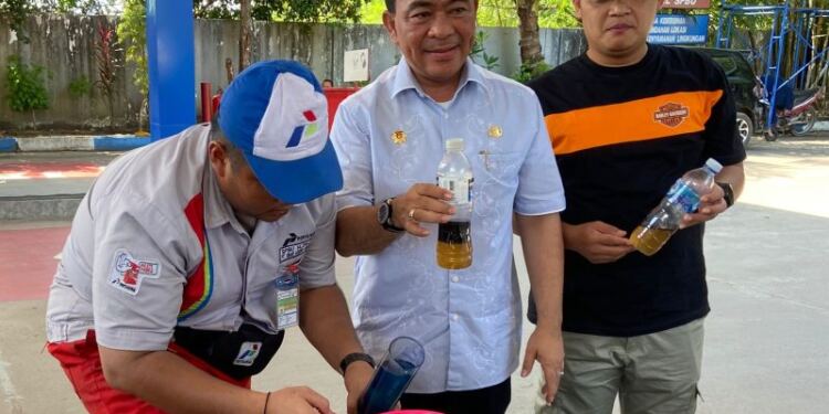 Kepala Disperindag Kota Batam, Gustian Riau (tengah) menunjukkan BBM jenis Pertamax 92 bercampur air di SPBU KDA, Kota Batam. (Foto/Net)