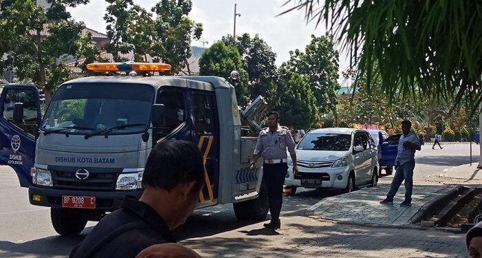 Petugas Dishub Batam menderek paksa kendaran yang parkir liar di tepi jalan Batam Center. (foto/net)
