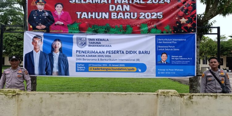 Personil Polsek Belitang II memasang banner di depan kantor Polsek Belitang II, Desa Sumber Jaya, Kecamatan Belitang II.