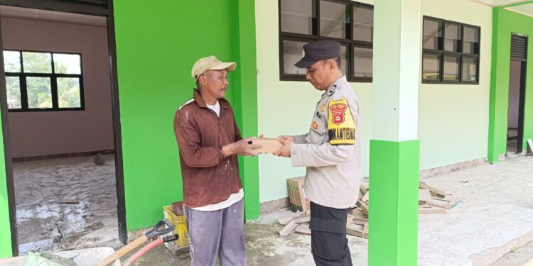 Kanit Binmas Aiptu Eko Budi Santo membagikan nasi kotak kepada warga kuli bangunan yang berada di Desa Kelirejo Kecamatan Belitang II, Jum'at, 31 Januari 2025. (foto/Yesi)
