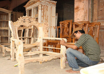 Seorang pria mengerjakan mebel kayu. (foto/ist)