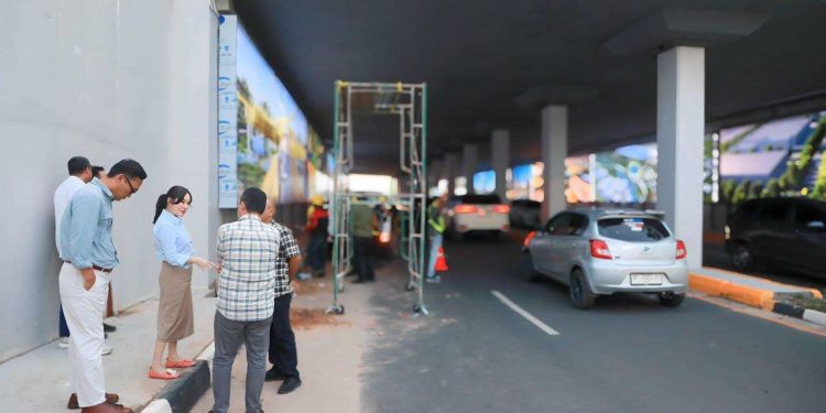 BATAM, RMNEWS.ID-BP Batam terus melanjutkan proses peremajaan Underpass Pelita sebagai bagian dari komitmen meningkatkan kualitas infrastruktur, keselamatan, kenyamanan, serta memperkuat estetika kawasan perkotaan bagi masyarakat.
Program revitalisasi ini merupakan tindak lanjut arahan Kepala BP Batam, Amsakar Achmad, bersama Wakil Kepala BP Batam, Li Claudia Chandra, yang menempatkan peningkatan kualitas infrastruktur publik sebagai salah satu prioritas pelayanan kepada masyarakat.
Revitalisasi Underpass Pelita tidak hanya difokuskan pada aspek fisik, tetapi juga peningkatan kualitas pelayanan publik melalui infrastruktur yang lebih aman, nyaman, fungsional, dan memiliki nilai estetika sebagai representasi kemajuan Kota Batam.
Hingga saat ini, sejumlah pekerjaan utama telah diselesaikan. Sementara itu, beberapa tahapan penyempurnaan masih terus berlangsung.
Anggota/Deputi Bidang Infrastruktur BP Batam, Mouris Limanto, mengatakan bahwa seluruh proses peremajaan dilakukan dengan tetap menjaga struktur utama underpass agar tidak memengaruhi kekuatan konstruksi bangunan.
“Kami berusaha untuk tidak menyentuh struktur utama underpass agar tidak mempengaruhi kekuatannya, sehingga kami menghindari pengeboran pada bagian atap underpass,” ujar Mouris.
Saat ini, pekerjaan difokuskan pada pembuatan tutup drainase serta penambahan struktur penguat lightbox agar lebih kokoh, stabil, dan memiliki daya tahan yang lebih baik.
Sebagai bagian dari peningkatan aspek keamanan, BP Batam juga telah memasang sejumlah titik kamera pengawas (CCTV) di kawasan underpass untuk mendukung pengawasan terhadap fasilitas publik serta mencegah terjadinya aksi vandalisme maupun pencurian komponen infrastruktur.
Mouris menambahkan, proses peremajaan Underpass Pelita ditargetkan rampung pada akhir Juli 2026, sehingga seluruh fasilitas dapat segera berfungsi secara optimal dan memberikan manfaat maksimal bagi masyarakat.
BP Batam juga mengajak seluruh masyarakat untuk bersama-sama menjaga fasilitas umum yang telah dibangun agar tetap bersih, aman, dan terhindar dari aksi vandalisme, sehingga manfaatnya dapat dirasakan secara berkelanjutan oleh seluruh pengguna jalan.***(rm/humas).