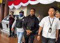 tersangka Basri dengan tangan diborgol di apit dngan dua petugas Polisi dari Bareskrim Polri. (Foto/Dokumentasi).