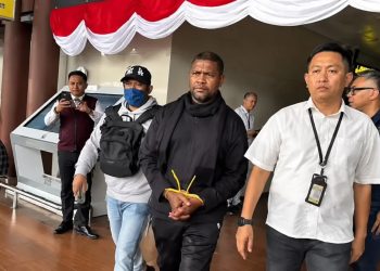 tersangka Basri dengan tangan diborgol di apit dngan dua petugas Polisi dari Bareskrim Polri. (Foto/Dokumentasi).