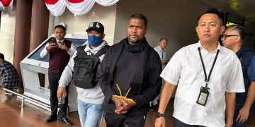 tersangka Basri dengan tangan diborgol di apit dngan dua petugas Polisi dari Bareskrim Polri. (Foto/Dokumentasi).
