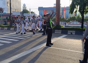 Personil Polres Langkat Bantu Penyeberangan Siswa Sekolah dan Urai Kemacetan. (Foto/Jhon).