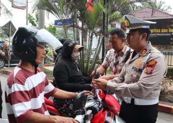Sejumlah Personil Polres Langkat Bagikan Bendera Merah Putih Kepada Masyarakat. (Foto/Jhon).