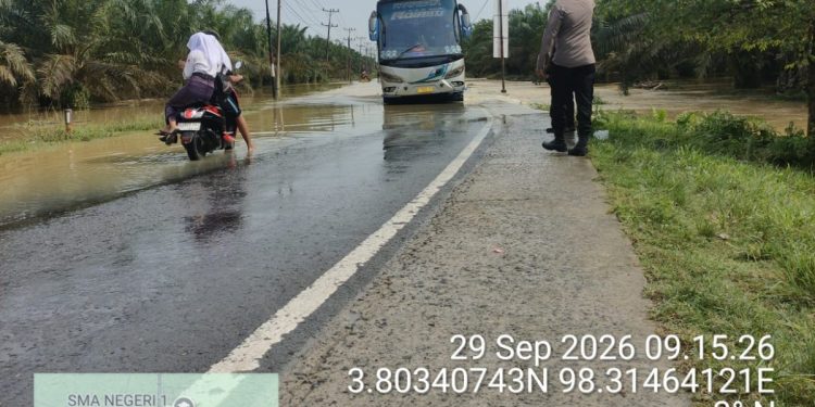 Banjir Rendam Jalan Sumor bor-Tanjung Selamat, Polsek Padang Tualang Sigap Atur Lalu Lintas. (Foto/Jhon).